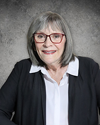 Headshot of Diane Krider wearing glasses and a black blazer in front of a soft grey backdrop.