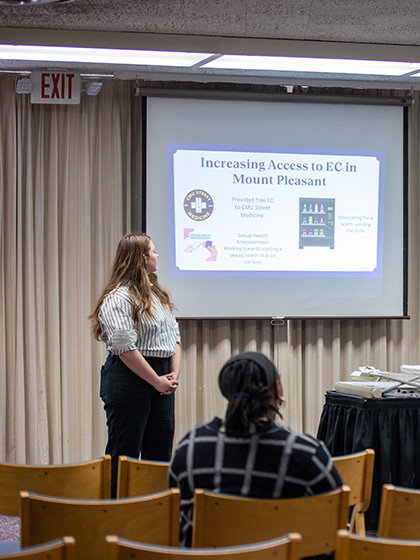 A woman dressed professionally gives a presentation to a group.