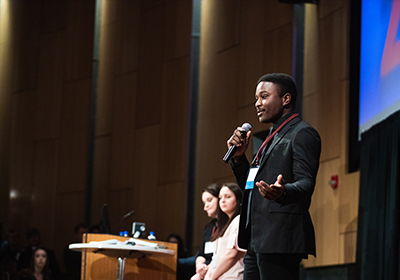 A student is on a stage giving a speech to an audience.