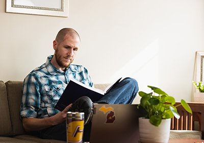 Graduate student studies while sitting on a couch in the graduate housing on campus.