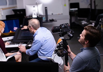 Student has a camera set up and is filming another student working on an animation project.