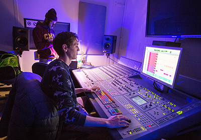 A student works the sound board in the record studio control room.