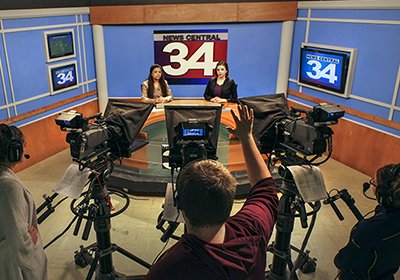 Two students are anchors at the news desk while three other students man the television cameras on News Central, a new station on campus.