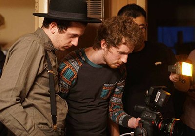 Two students watch the digital screen on their camera to see how a shot looks in the film they are making.