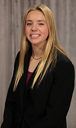 Headshot of Sarah Kelly in front of a soft grey curtain backdrop