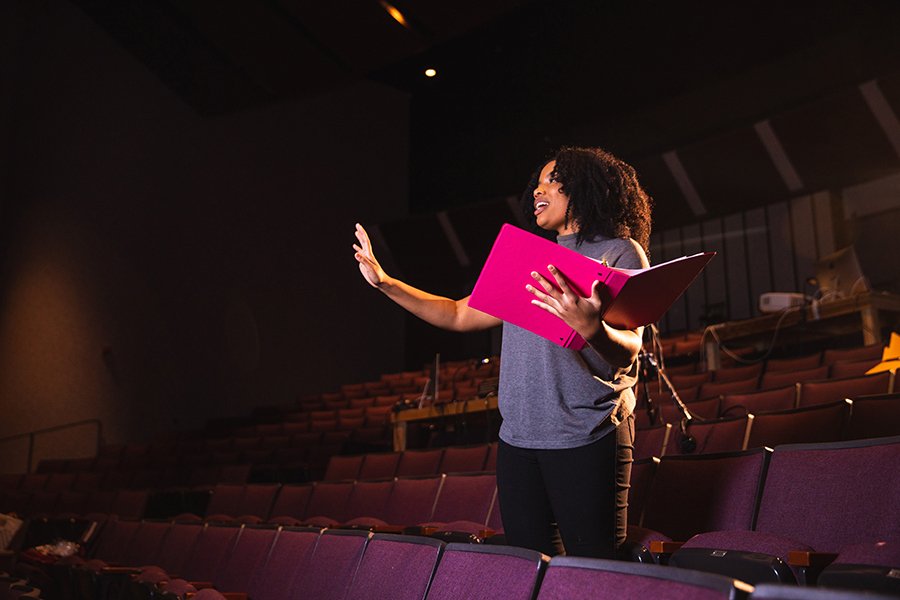 Woman directing a theatre production, talking to the cast