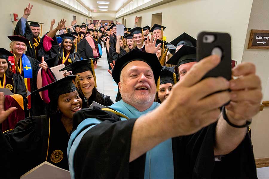 Large group of students smiling for a selfie on commencement day.