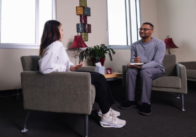 A man and woman sitting in chairs across from each other in a counseling room.