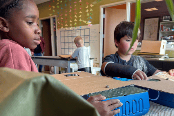 image shows two children cutting cardboard on a chompsaw
