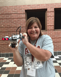 Kim June stands facing the camera. She is holding a robot and smiling.