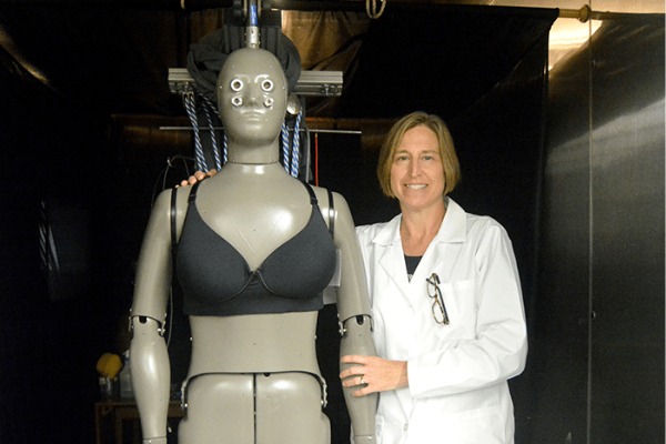 A woman standing next to a thermal manikin.