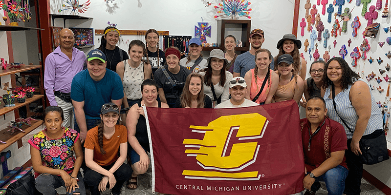 Students on a study abroad trip holding CMU flag