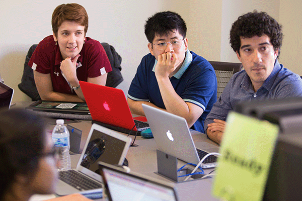 Three CMU students in a classroom with laptops