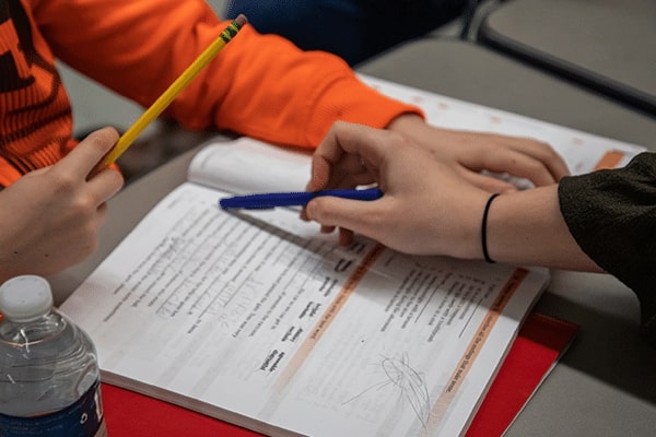 Hand pointing to a sentence in a book