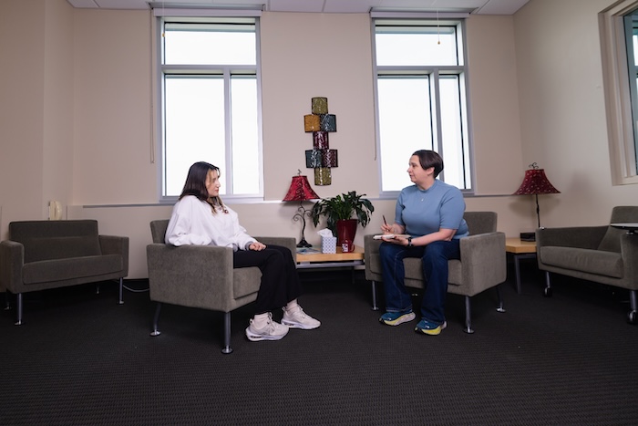 A counselor sitting with a patient in a room.