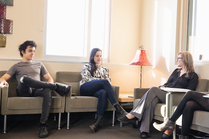 A counselor sitting with two patients in a room.