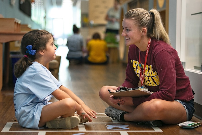 A school counselor and young child sitting together on the floor.