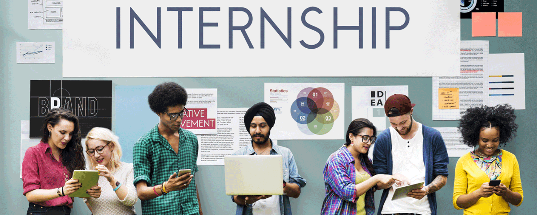 group of diverse students standing looking at their devices