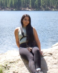 Emily Awad sitting on a rock in front of a lake.