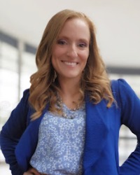 Chrissandra Padilla smiling at camera with a grey wall and window behind her.