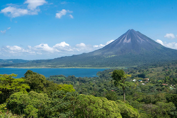 Volcano Arenal in Costa Rica the background with water and forest in the foreground.