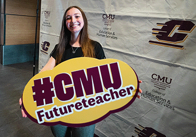 Future Central Michigan University educator holding a #CMUFutureteacher sign.