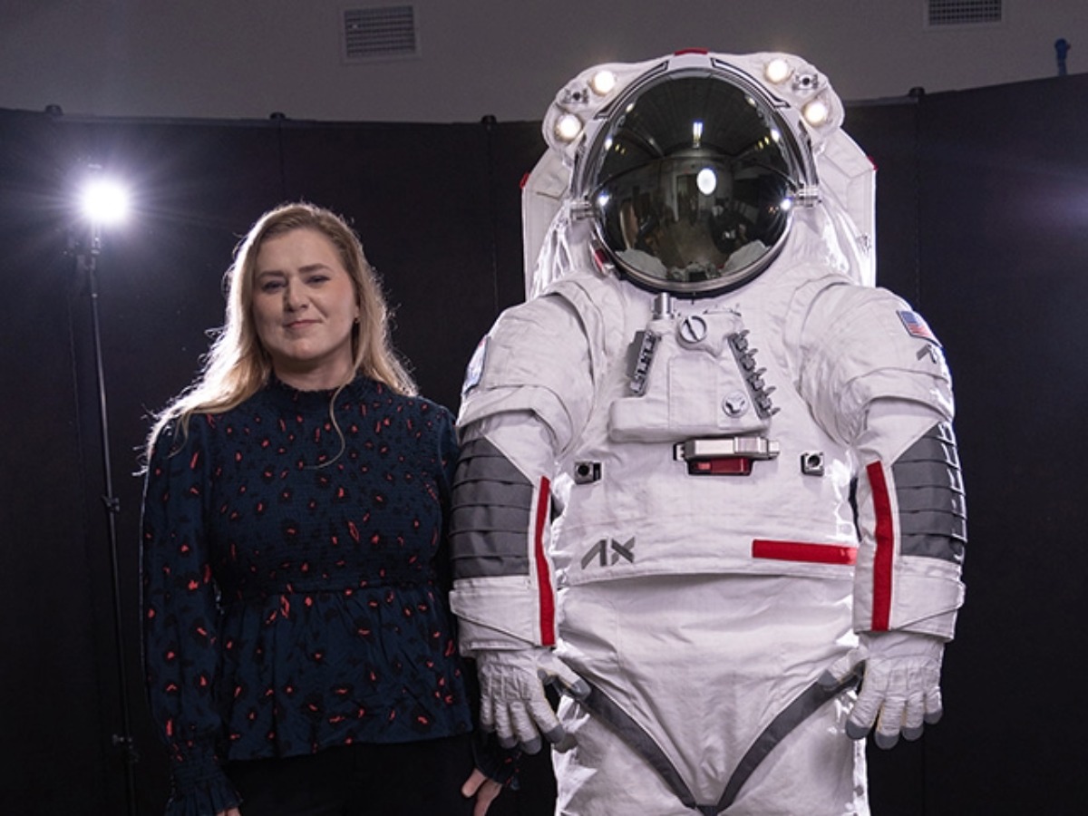 Falanne Jenkins standing next to a space suit.