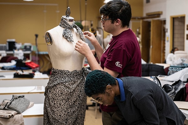 two boys and a manikin designing an outfit.