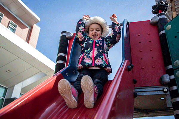 child going down slide on playground