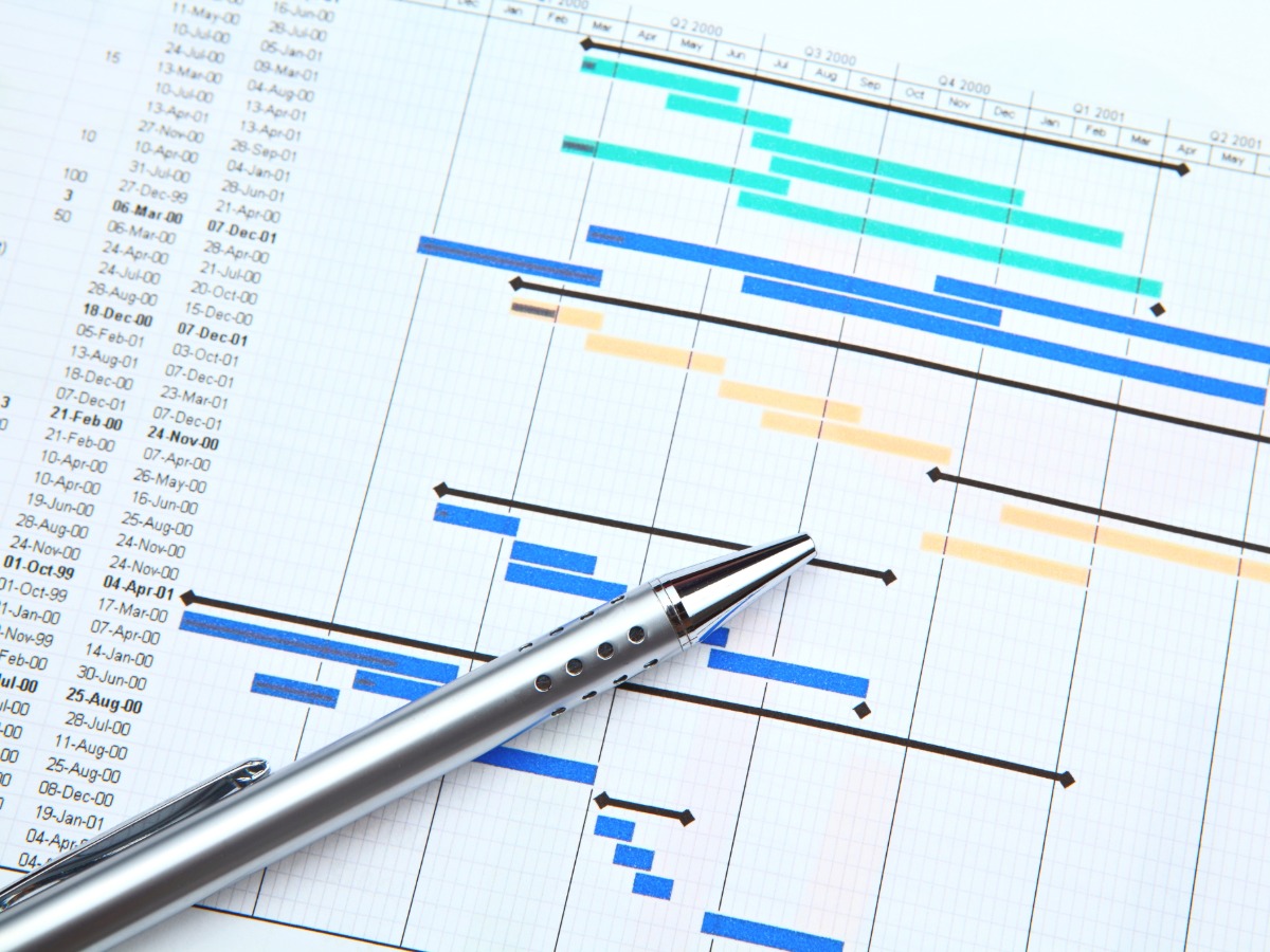 A project management timeline spreadsheet and pen.