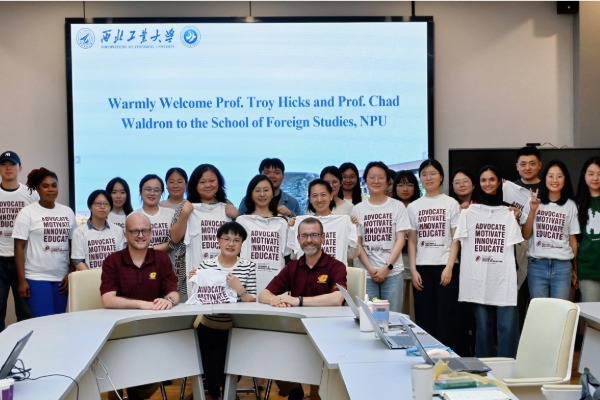 A group of people standing in a room all wearing CMU Teacher Education t-shirts.