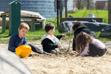 A group of children playing in sand at the CDLL outdoor play space.