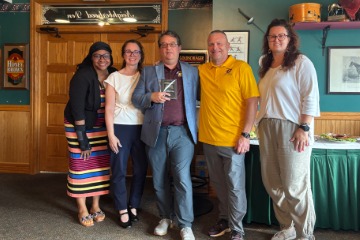 Lubig holding his award plaque and posing for a photo with the Ed.D. Alumni Board.