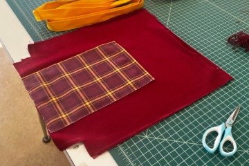 A piece of the tartan fabric laying on a green table.