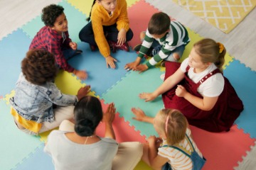 A group of young children at school sitting on a play mat.