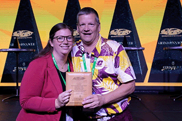 Tim Otteman, faculty member in the Department of Recreation, Parks and Leisure Services and Kat Paye - Executive Director of the National Cherry Festival and Chair-Elect of the IFEA Foundation Board of Directors holding the Gold Pinnacle Award.