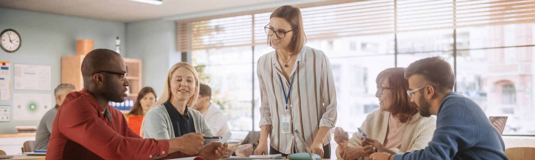 Five adults talking and gathered around a table in a classroom