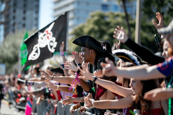 A crowd of people standing along a fence outside during a parade.