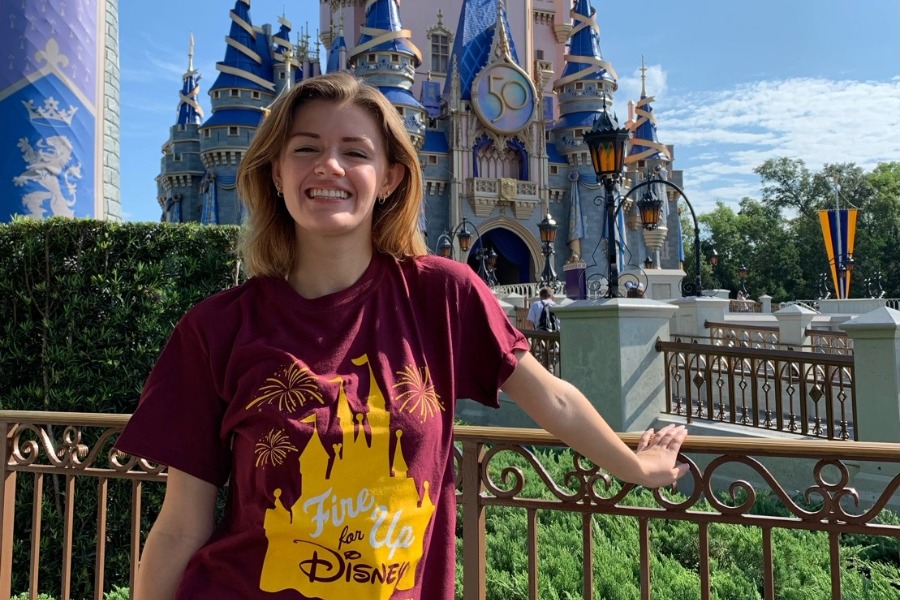 A student wearing a CMU Disney College Program t-shirt and standing in front of the Disney Castle.