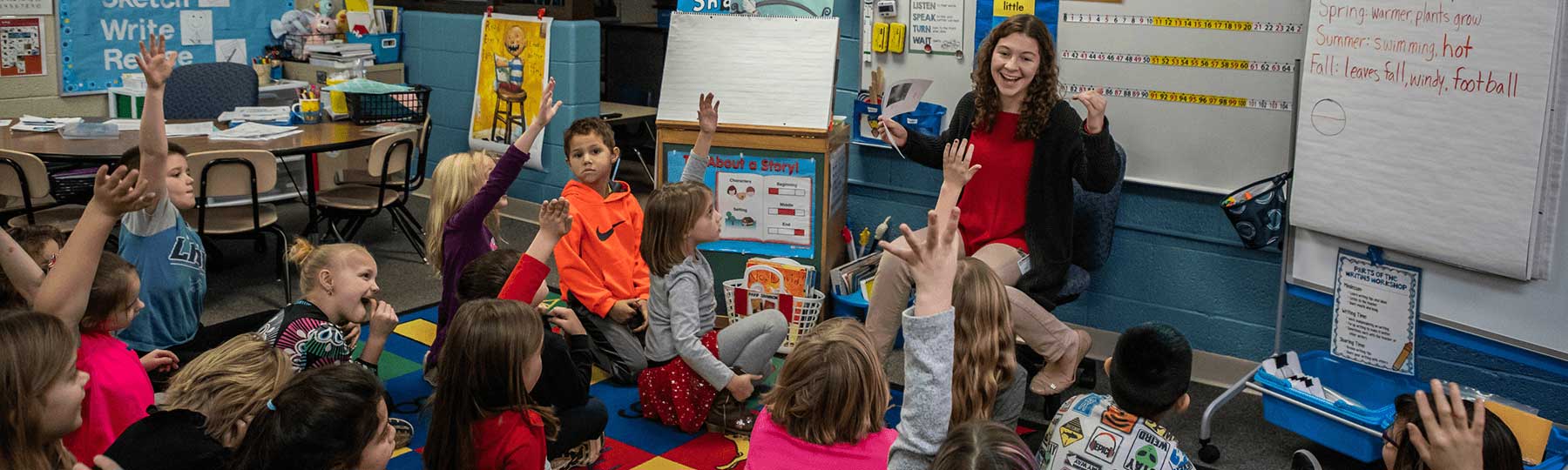 Teacher in a classroom with children sitting on the floor
