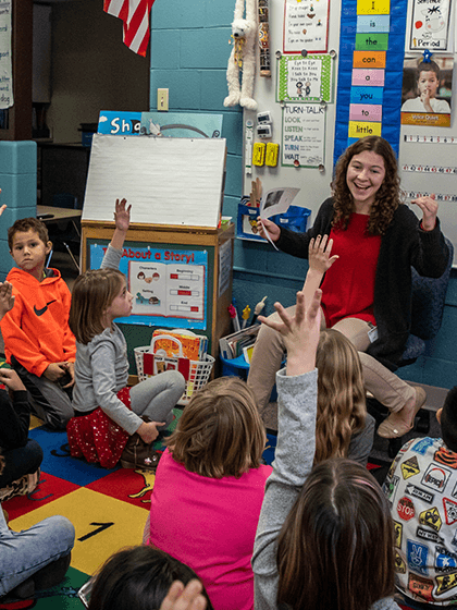 Teacher in a classroom with a groups of children sitting on the floor