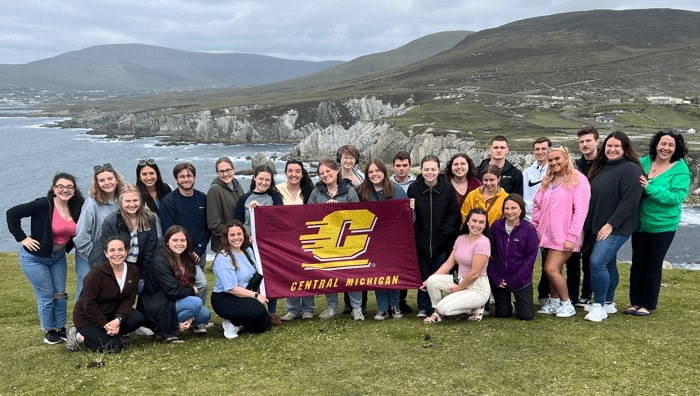 Group photo of CMU students holding a CMU flag