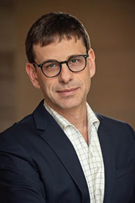 Closeup image of Jeffrey Veidlinger wearing white striped shirt and dark suit jacket.