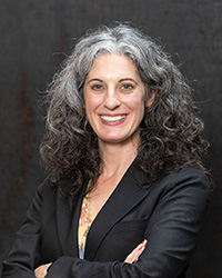 Closeup image of Alexis Herr wearing a black suit with her arms crossed lightly