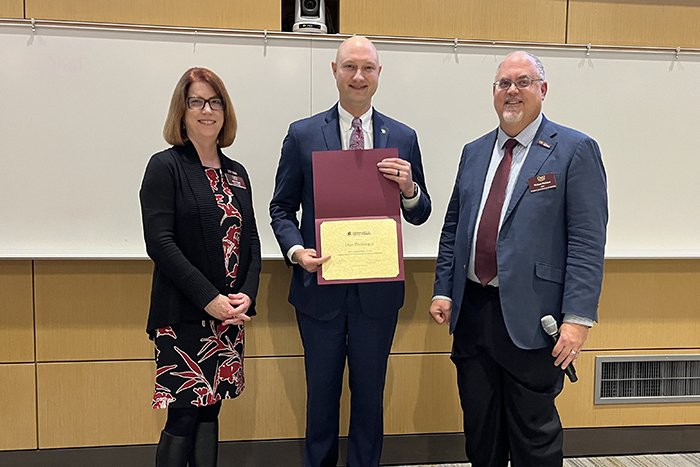 Alumni award recipient Dan Eichinger holds a certificate and stands between Associate Dean Marcy Taylor and Dean Richard Rothaus.