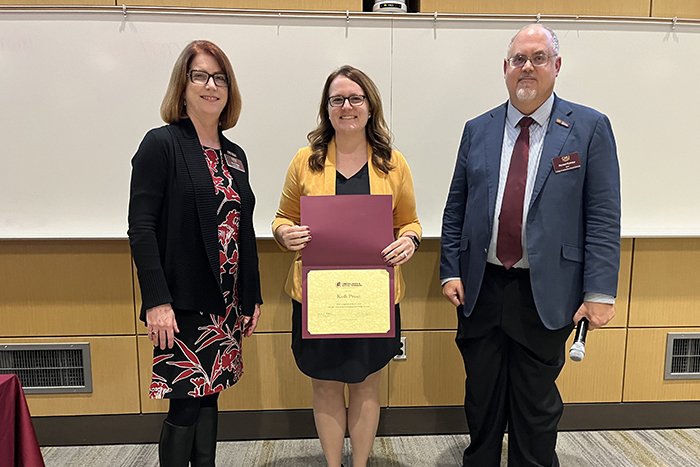 Alumni award recipient Kadi Prout holds a certificate and stands between Associate Dean Marcy Taylor and Dean Richard Rothaus.
