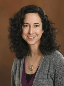 Professional headshot of Larissa Niec in dark attire against a brown background.