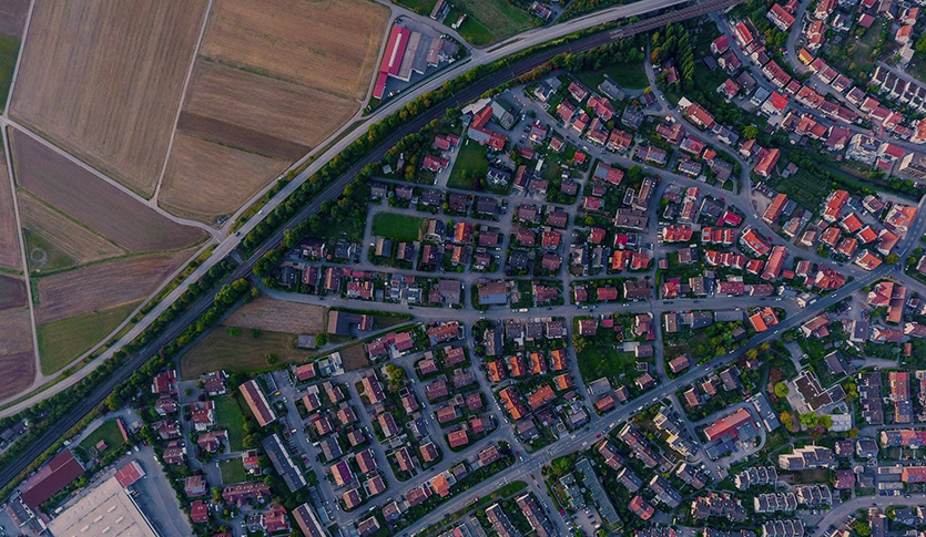 Image of a large highway separating rows of houses from farm fields.