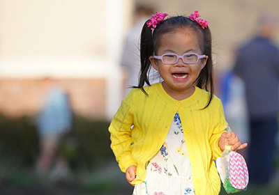 Image of young child wearing yellow sweater and glasses.