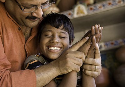 Man and child embracing and touching hands.